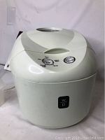 White Wolfgang Puck mini breadmaker with two dials, front logo, and power cord visible.