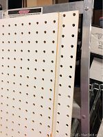 Close-up showing the holes and edge of a white pegboard, demonstrating condition and material