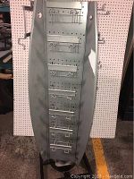 Front view of the metal pegboard panel with attached wire hooks and display shelves.