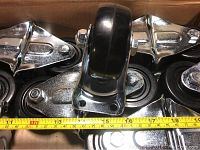 Close-up of several 3-inch hard rubber swivel casters with chrome mounting plates, with measuring tape showing 3 inches wheel diameter.