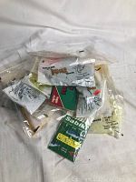 Top view of assorted fishing lures and fishing tackle packages including several sealed plastic bags with paper labels and one cardboard branded package.