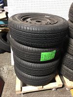 Four Rovelo all season tires stacked on a wooden pallet, showing tires mounted on steel rims.