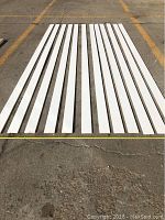 Twelve flat baseboards laid out on the pavement, showing total quantity and length per piece.