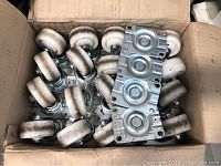 Box containing 20 white nylon swivel wheel castors with metal mounting plates.