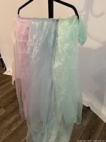 Pastel pink, light blue and mint green sheer fabric lengths draped over hanger