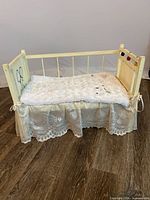 cradle front view showing hand-painted panel, lace skirt and mattress