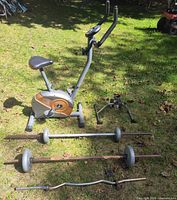 Overall lot view with stationary bike, three weight bars and pedal exerciser