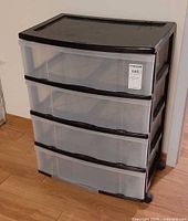 Front angled view showing three clear drawers, black frame, casters