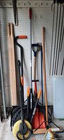 Full group of long-handled tools leaning on pegboard