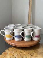 Set of 12 striped ceramic mugs grouped on a wooden tray