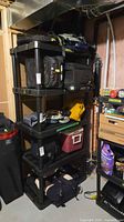 Full view of black plastic four-shelf unit with items on shelves