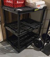 Front view of three-tier black plastic shelving unit