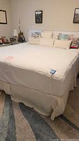 full view of quilted mattress pad on queen bed with pillows visible