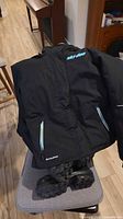 Front view Ski-Doo jacket draped on chair with boots underneath