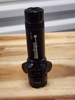 Cylindrical black GL6 laser sight showing adjustment turrets and housing markings