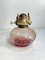 Front view of cranberry hobnail glass oil lamp with brass burner