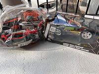 Boxed RC car and clear bag of loose toy cars on floor