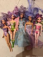 Group shot of five purple hair Barbie dolls with assorted outfits