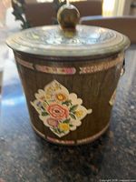 Full view of floral metal container with lid and knob