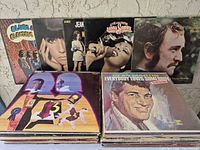 First photo showing two stacks of records with back-row display including Blues & Electric, Jean, Donna Summer, Richard Harris; front stacks topped by abstract number 3 cover and Dean Martin.