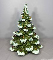 Full front view of ceramic Christmas tree showing snow accents and bulbs