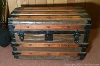 Front view of the wooden storage trunk showing metal latch and reinforcement hardware