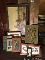 All framed art pieces together showing large landscape painting, embroidery and smaller prints.