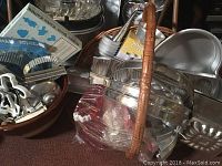 Photo showing metal cookie cutters, mixing bowls in metal and glass, and a wicker basket holding some items.