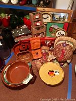 Photo showing entire collection of holiday decor items including turkey figurines, decorative dishes, framed pictures, cookie jar, and fabric towels.