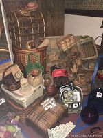 View of assorted wicker baskets piled with a small upholstered footstool and basket holding picture frames in front