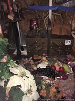 Wooden sewing box with assorted artificial fruit and floral decor arranged in front and on top