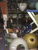 Photo showing assortment of metal and glass lamp bases, stained glass shade, small lamp parts, and yellow lamp shade.