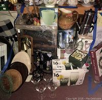Wide shot showing array of drinkware, trays, decorative mushroom items, brass candlesticks, pitchers, and boxed hair clipper kit.