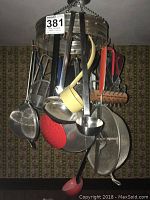 Hanging rack filled with metal and plastic ladles, red colander, strainers, and other kitchen utensils