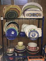 Photo showing multiple shelves with serving plates, platters, and bowls arranged by size and design.