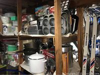 Shelves with plastic Tupperware containers, pitchers, bowls, and lids in various sizes and colors, mainly green and clear.