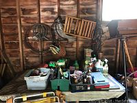 Overview of table with assorted garden tools and supplies against wooden wall with items hanging above