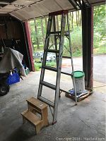 6 ft Werner aluminum ladder and 15 inch wooden step stool together in garage