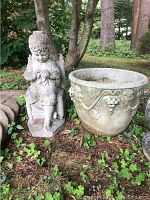 Planter and seated child statue side by side on ground