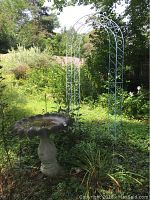 Overall view of cement bird bath and metal trellis outdoors