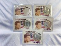 Group shot of five individually packaged Kennedy half dollars