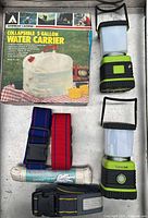 All lot contents displayed on tray: boxed water carrier, two lanterns, three straps, rope