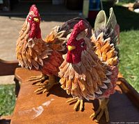 Front view of both handmade rooster figurines on table outdoors