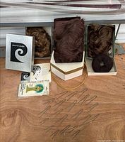Overview showing three boxed wigs, bun hairpiece, pins, booklet, cleaner packet