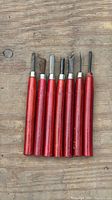 Full set of seven red-handled carving tools laid out