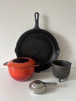 Front view of all cookware: Findlay skillet, red fondue pot with lid, stainless burner, small footed cauldron