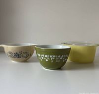 Front view of three Pyrex bowls showing patterns and lid
