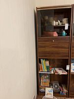 Full view of cabinet showing glass door section, drop front and shelves