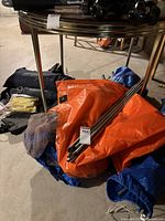 Tarps, metal poles, grommet package and mesh panels grouped on floor