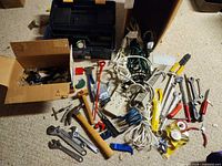 Overall view of mixed tools, cords, toolbox, hardware on carpet